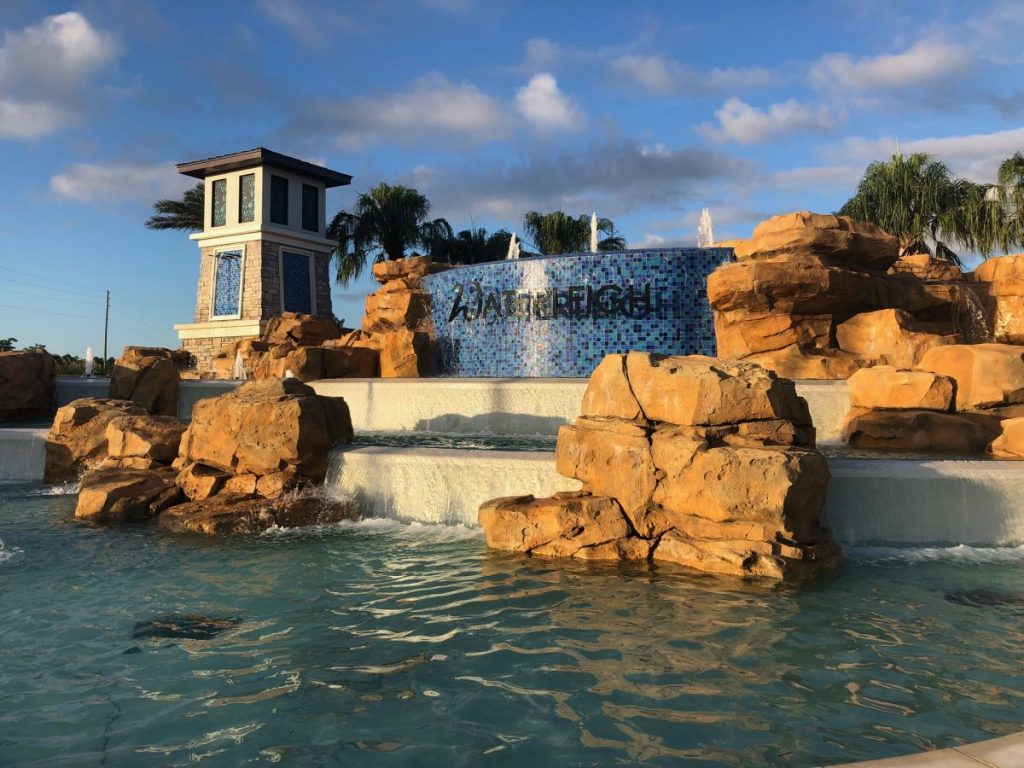 A large water feature that includes a pond and cascading waterfall, rockwork, and signage for the Waterleigh entry in Orlando.