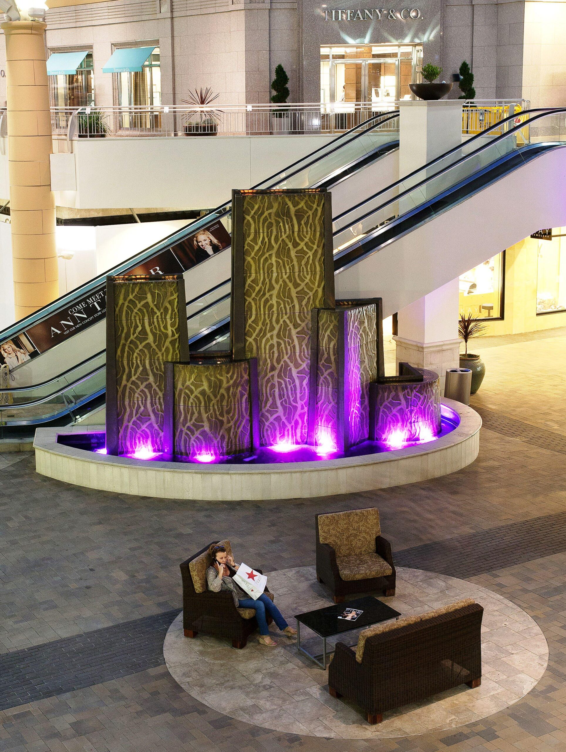 Fashion valley western fnt A sculpture water fountain with ornate detailed pillars and purple up-lighting, featured at Fashion Valley.