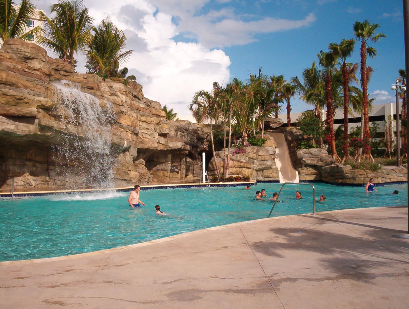 Hardrock slide A large outdoor waterpark pool and slide at the Hard Rock Hotel featuring a waterfall water feature, trees, and artificial rockwork.