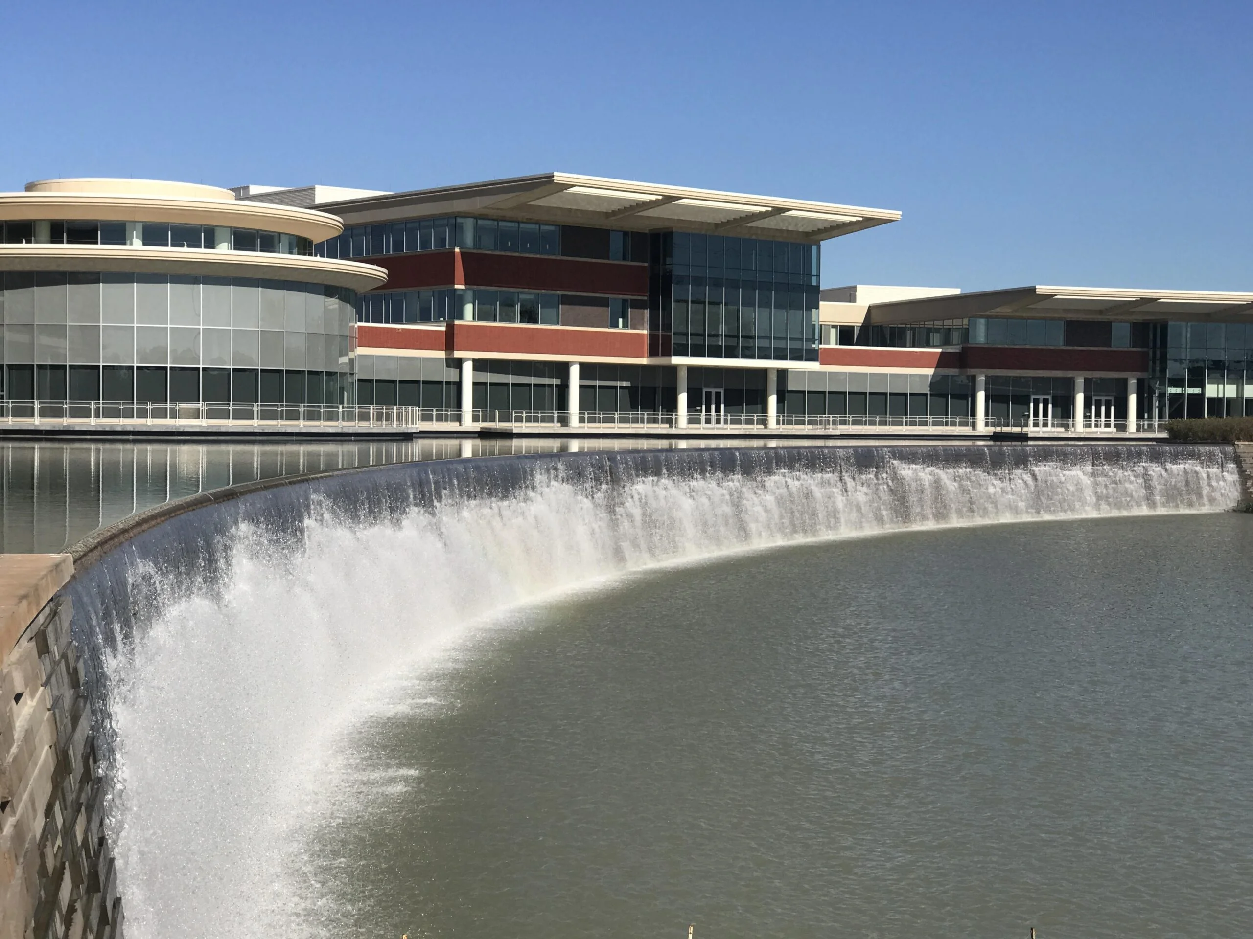 Nw hospital 3 An expansive water feature outside of a large, modern hospital featuring waterfall fountains and a large pond.