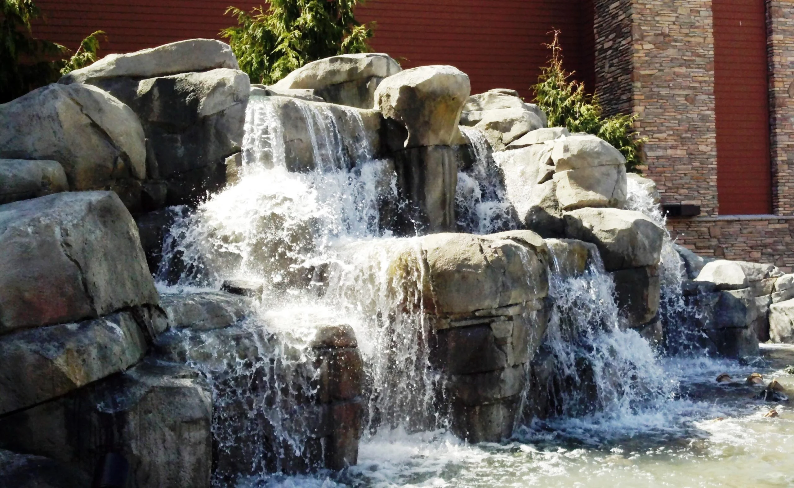Silverreef casino A fast flowing water fall spills over giant stacked rocks and boulders, into a wading pool.